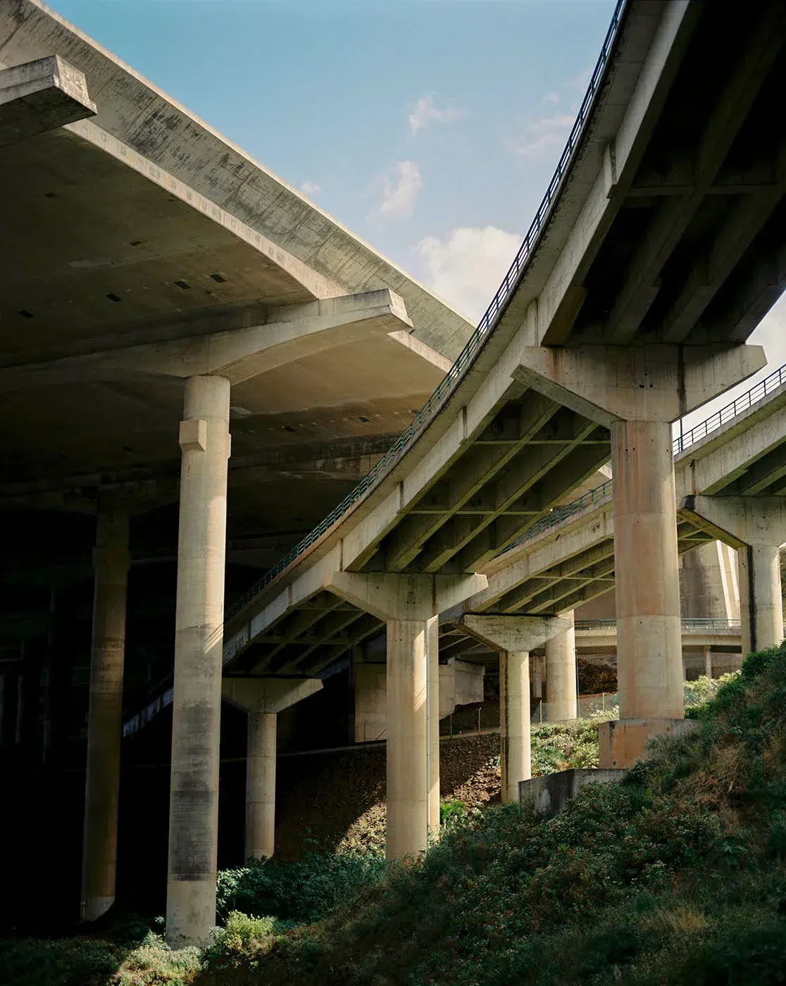 Concrete viaducts overlap above a slope covered in vegetation.