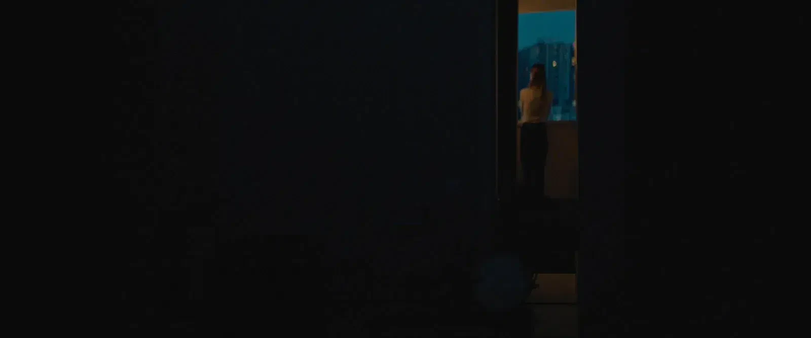 Um interior escuro com uma porta aberta para uma zona iluminada.