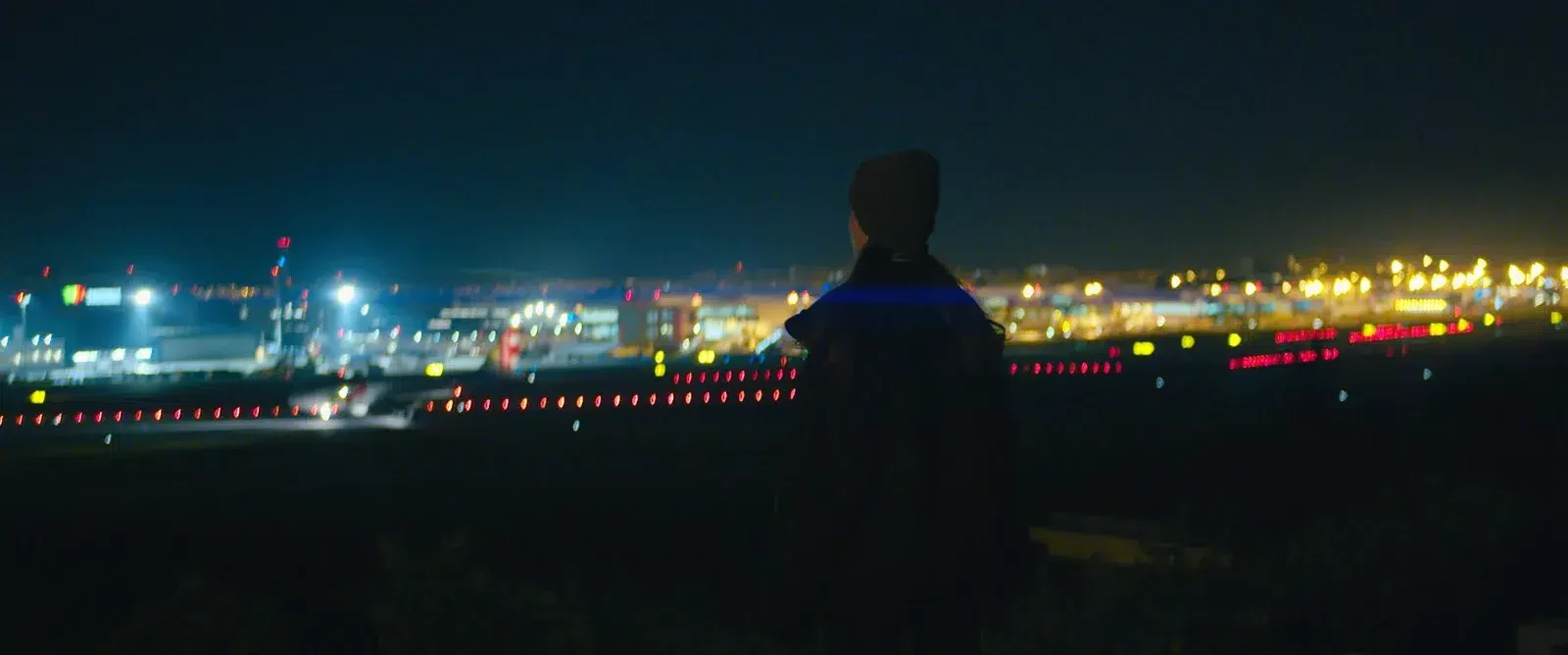 A silhueta de uma pessoa perante uma paisagem iluminada à noite.